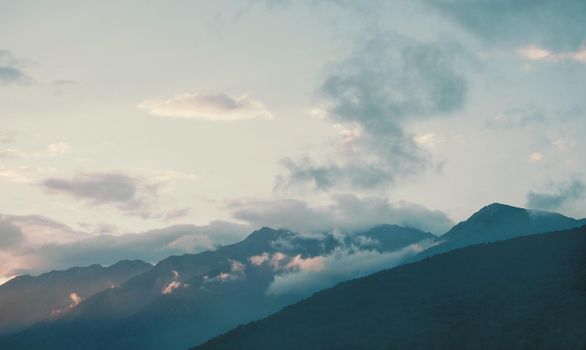 Sky with clouds over mountain ridge in blue colors.