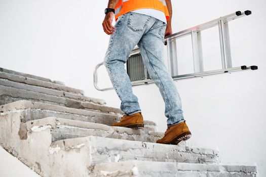 Professional builder carrying metal ladder, close up photo