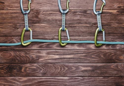 Rope with quickdraws on a wooden background, top view. Copy-space in lower part of the image.