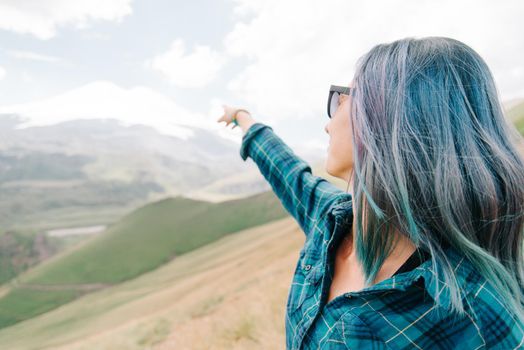 Explorer young woman pointing at snowy high mountain outdoor.