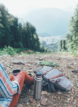 Unrecognizable female traveler rests with cup of tea outdoor.