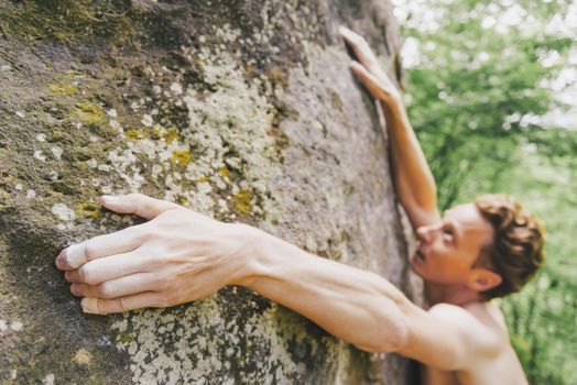 porty young man climbing bouldering on rock wall outdoor.