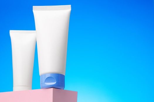 Blank white cosmetic container against blue background, copy space