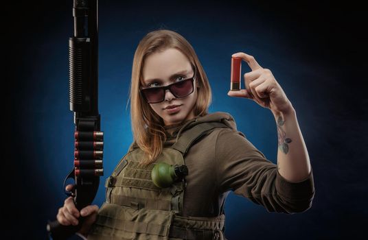 girl in military overalls airsoft posing with a gun in his hands on a dark background