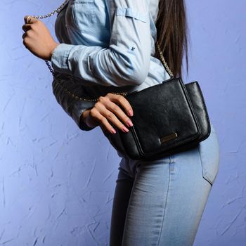 Fashionable woman in denim shirt and jeans with a black bag in her hands