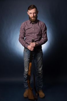 Man in a plaid shirt with shotgun on a dark background