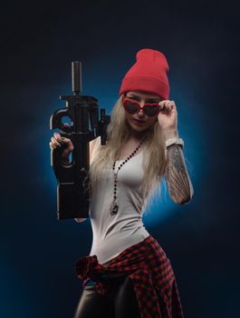 bright blonde in a red hat with a submachine gun on a dark background