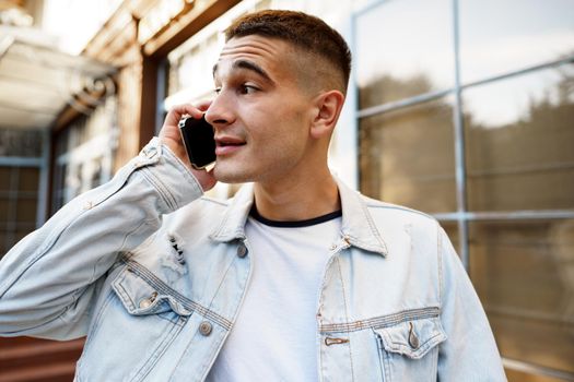 Young casual man walking on the city street and talking on the phone, close up portrait