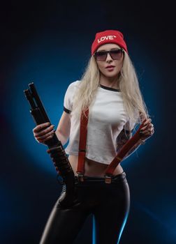 bright blonde in a red hat with a shotgun on a dark background