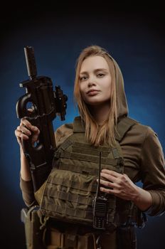 girl in military overalls airsoft posing with a gun in his hands on a dark background