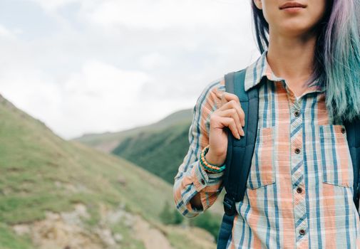 Smiling female backpacker walking in summer mountains.