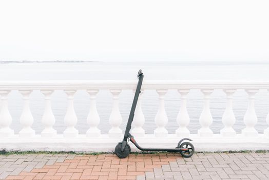 Ecological transport electric scooter on embankment in front of sea. No people.