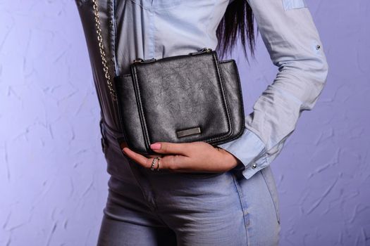 Stylish woman in jeans with small black handbag clutch. fashion concept.