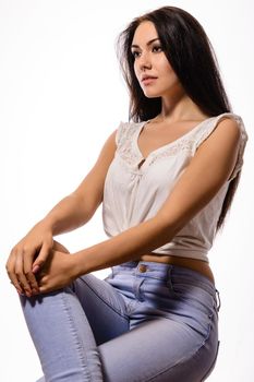 beautiful brunette woman in white tank top and jeans sitting on a hands on knees