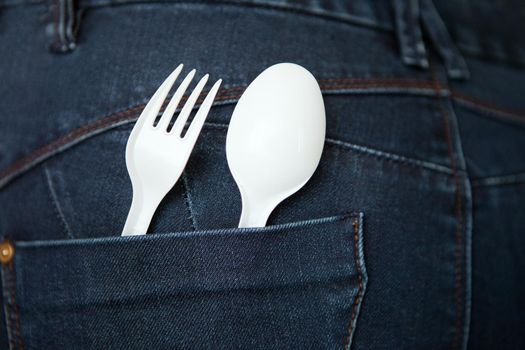 reusable plastic spoon and fork at the pocket. safe environment. Take Out Food Concept with Denim Jeans with a white Fork and Spoon in the Pocket. fast food concept.