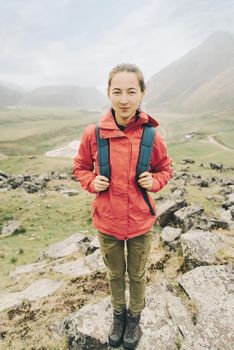 Hiker young woman standing in full-length outdoor, front view, looking at camera.
