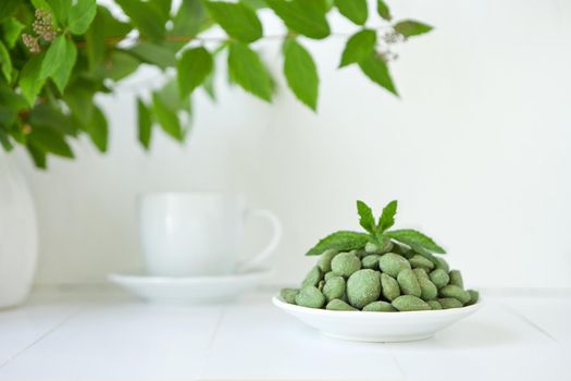 green nuts with wasaby or canabis coat on white plate on white background. Selection of healthy food for heart, life concept. eco nutrition.