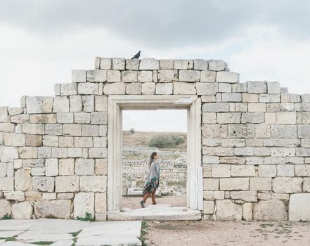 Beautiful young woman walking among the ancient ruins.