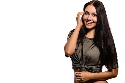 Portrait of attractive smiling brunette in a gray T-shirt with a knot tied in front