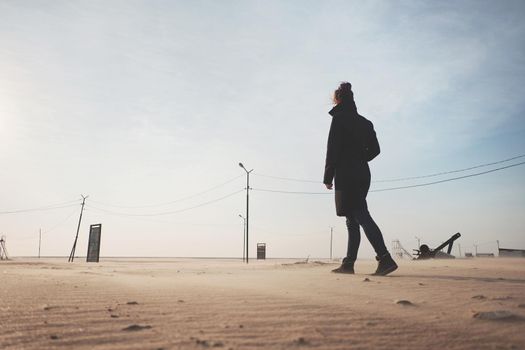 Young woman wearing in coat walking in the desert.