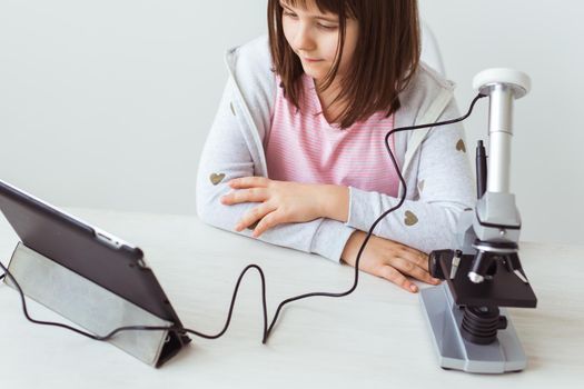 Portrait of cute little child doing homework with a digital microscope Technologies, science and children.