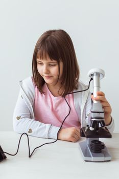 Child girl in science class using digital microscope. Technologies, children and learning.