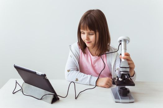 Portrait of cute little child doing homework with a digital microscope Technologies, science and children.