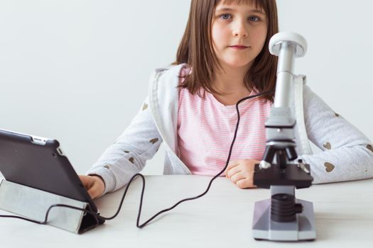 Child girl in science class using digital microscope. Technologies, children and learning.