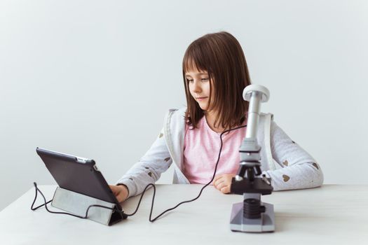 Schoolgirl using microscope in science class. Technologies, lessons and children.