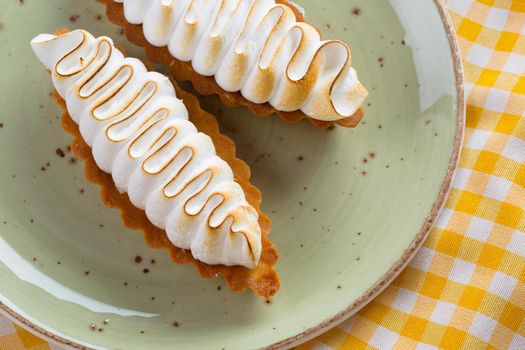 Lemon tart with meringue on green plate close up