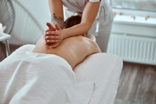 Professional confident massage master is doing procedures to caucasian woman in minimalistic modern cabinet