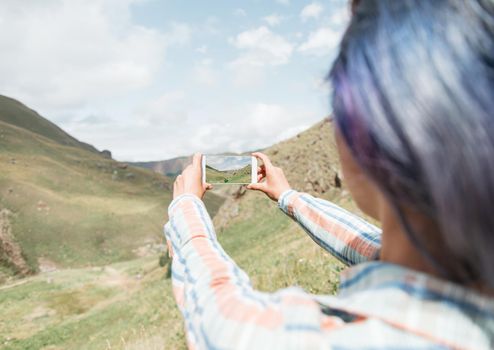 Traveler young woman taking photo with smartphone the mountain valley outdoor.