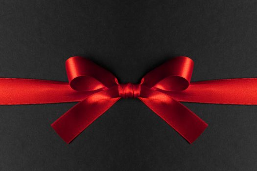 Red ribbon bow on black background, black friday of Christmas holiday gift