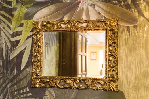 Luxury vintage mirror with gold frame on the wall. Isolated inside.