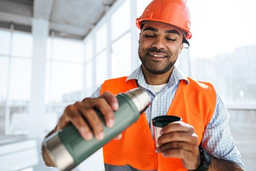 Portrait of a man worker in workwear on a break drink coffee and have rest, close up