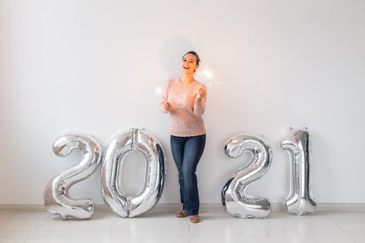 New Year celebration and party concept - Happy young woman with sparklers near silver 2021 balloons on white background