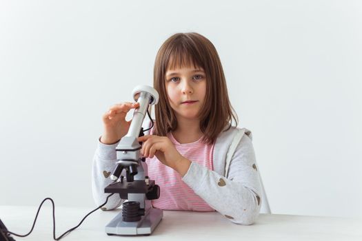 Schoolgirl using microscope in science class. Technologies, lessons and children.