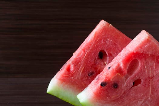 Slice of watermelon on a black plate on a dark background