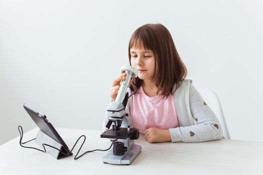 Portrait of cute little child doing homework with a digital microscope Technologies, science and children.