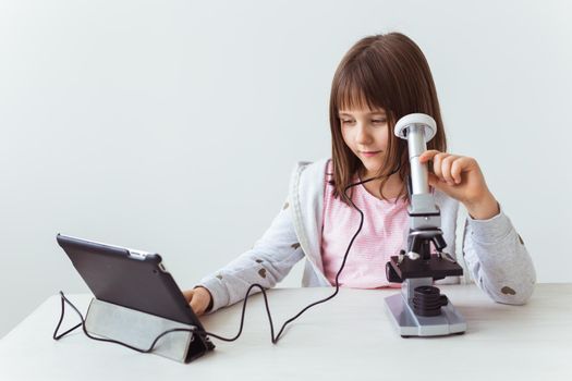 Portrait of cute little child doing homework with a digital microscope Technologies, science and children.