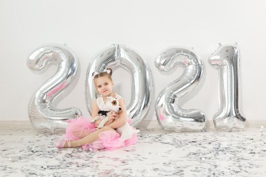 New year, holidays and celebration concept - Little girl sitting near with numbers balloons 2021