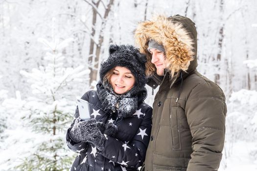 Season and relationship concept - Funny couple taking selfie in the winter time.