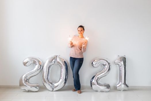 New Year celebration and party concept - Happy young woman with sparklers near silver 2021 balloons on white background