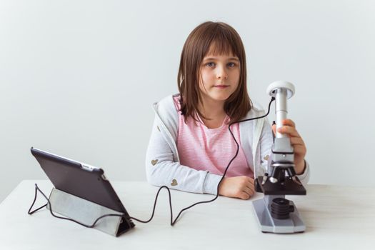 Schoolgirl using microscope in science class. Technologies, lessons and children.