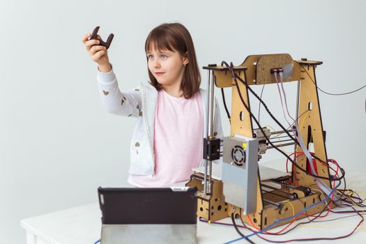 Cute girl with 3d printed shutter shades is watching her 3d printer as it prints her 3d model