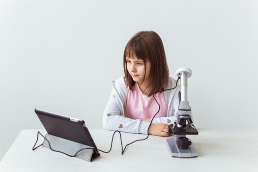 Schoolgirl using microscope in science class. Technologies, lessons and children.