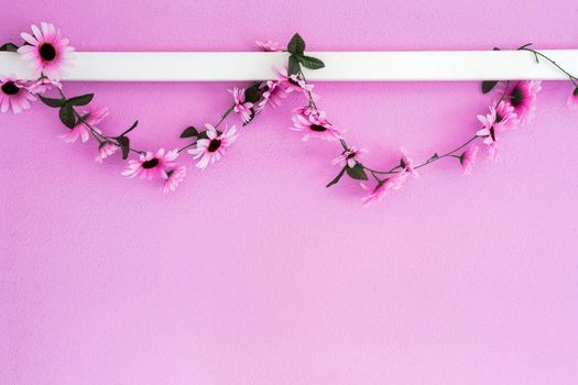 Cheerful, colorful pink, purple daisies garland hanging on pink wall background texture. beautiful modern design with copy space abstract decoration with flowers