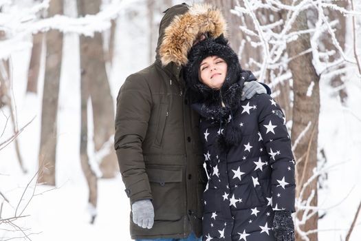 Fun, season and leisure concept - love couple plays winter wood on snow.