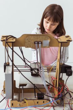 Cute girl with 3d printed shutter shades is watching her 3d printer as it prints her 3d model