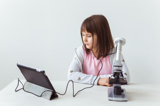 Child girl in science class using digital microscope. Technologies, children and learning.